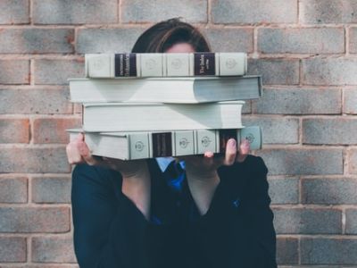 Photo of person holding pile of books.