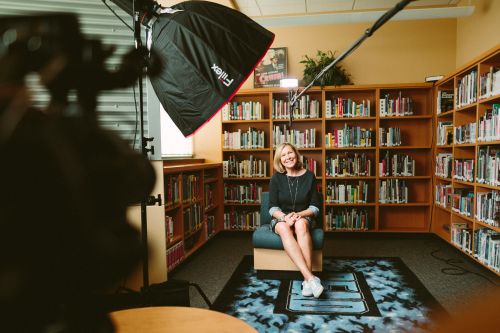 photo of a woman in front of bookshelves with a bright light in front of her