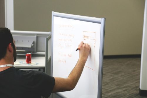 photo of a man writing on a whiteboard