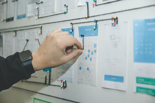 photo of a board with paper clippings and a hand pushing in a pushpin 