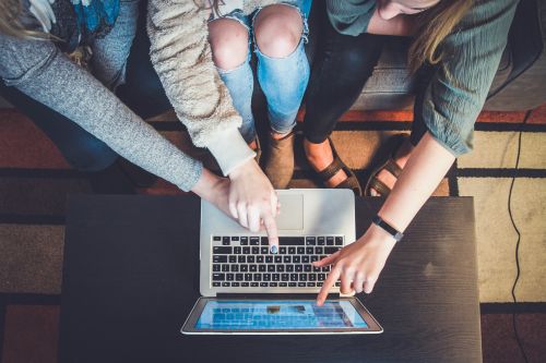 photo of several people in front of a laptop pointing to the screen