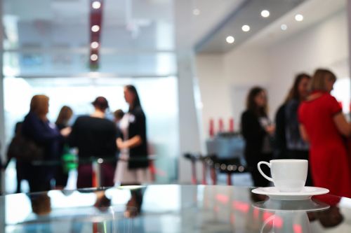 close up of a coffee cup and people in a social gathering