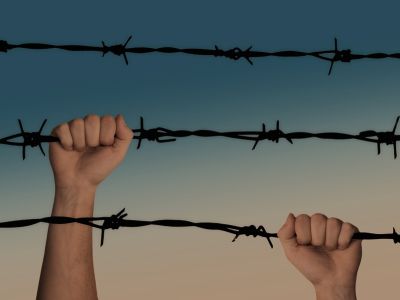 Image of hands grabbing barbed wire.