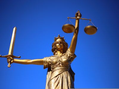 a photo of a Lady Liberty statue holding a scale in one hand and a sword in another against a blue background